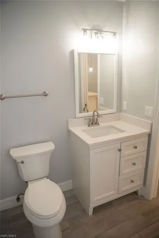Bathroom with hardwood / wood-style flooring, vanity, and toilet