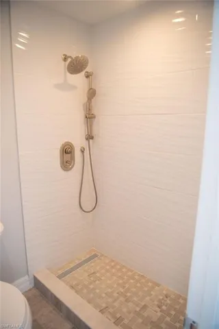 Bathroom featuring tiled shower and toilet