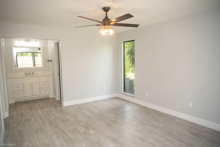 Unfurnished bedroom featuring ceiling fan, light hardwood / wood-style floors, and ensuite bath