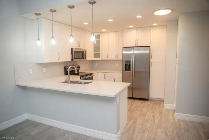 Kitchen with pendant lighting, stainless steel appliances, sink, and white cabinets