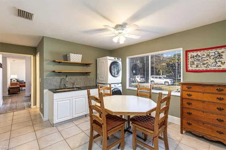 Dining space featuring stacked washing machine and dryer, light tile patterned flooring, and ceiling fan