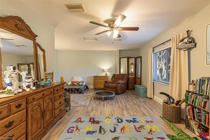 Living area featuring light wood finished floors, ceiling fan, and attic access