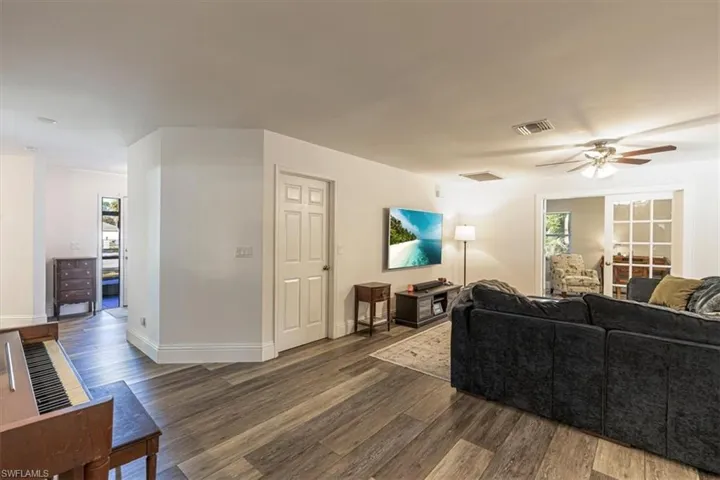 Living room featuring ceiling fan and dark wood-style floors
