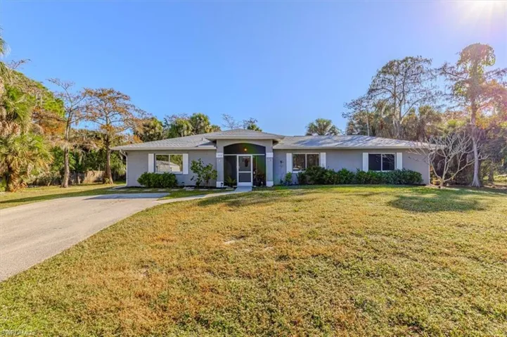Ranch-style house featuring a front lawn, stucco siding, and driveway