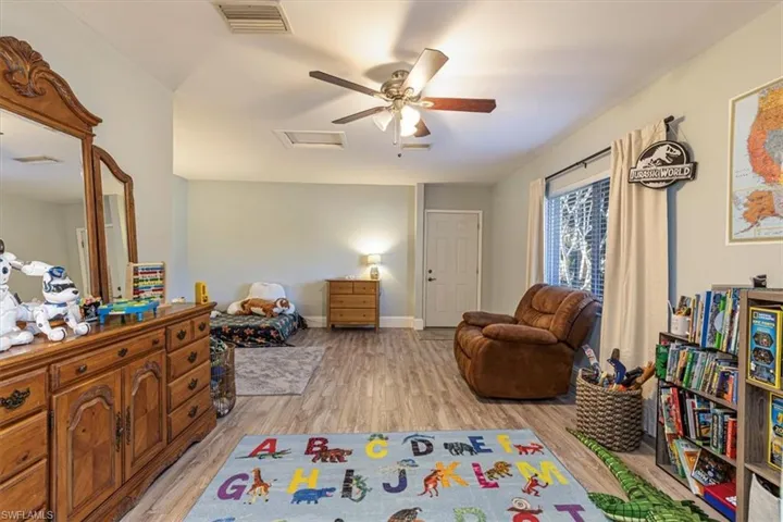 Bedroom with attic access, light wood-style flooring, and ceiling fan