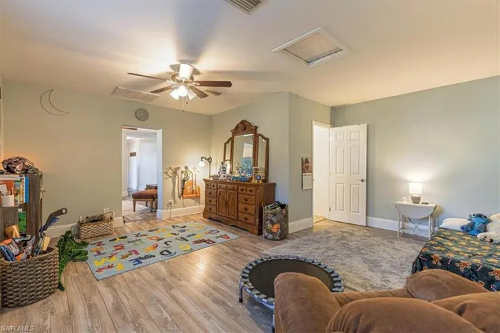 Bedroom with attic access, hardwood / wood-style floors, and a ceiling fan