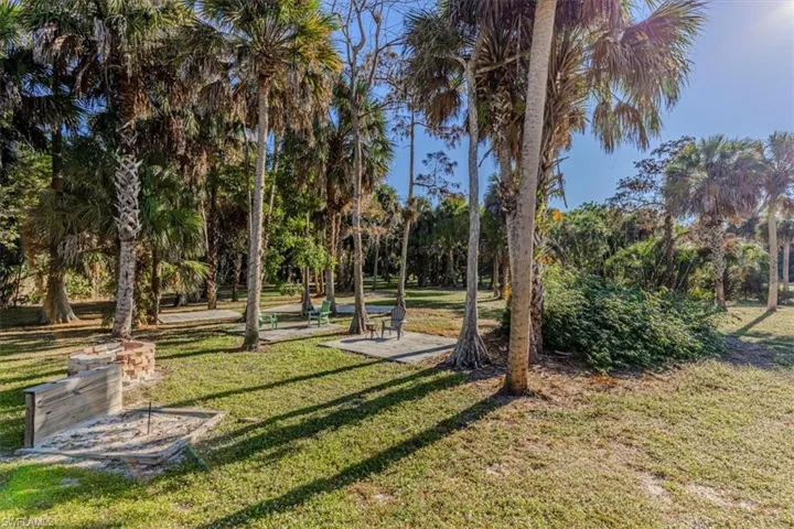 Surrounding community featuring a lawn, a patio area, and view of wooded area