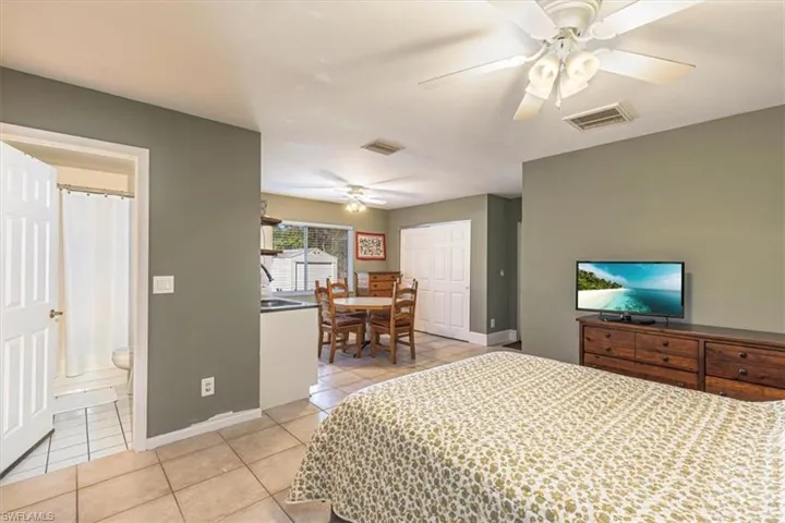 Bedroom with a closet, light tile patterned flooring, ceiling fan, and connected bathroom