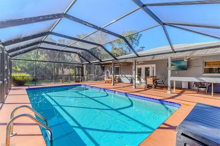 Swimming pool featuring ceiling fan, a lanai, a sunroom, french doors, and a patio