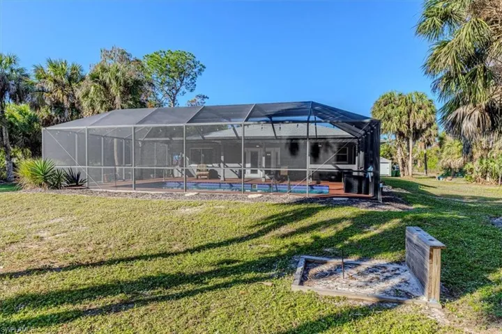 Rear view of property with a lanai, an outdoor pool, and a yard