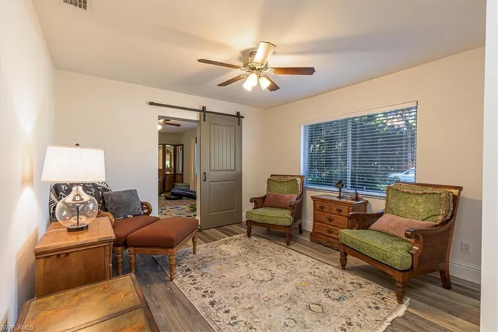 Sitting room with ceiling fan, a barn door, and wood finished floors