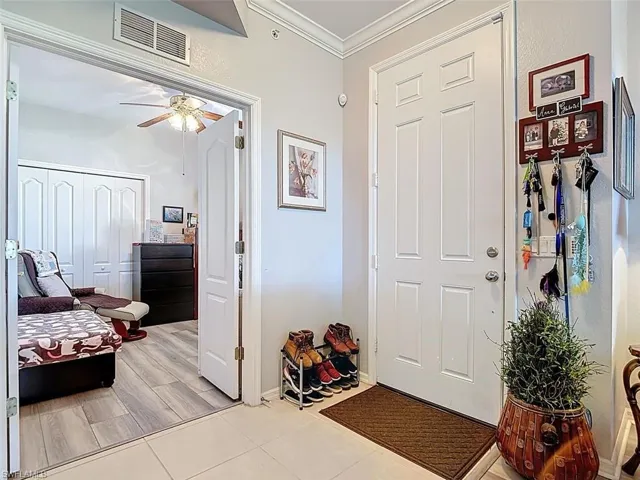 Entrance foyer with ornamental molding, ceiling fan, and wood finish floors