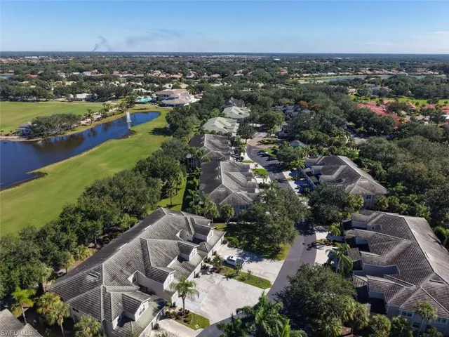 Aerial view of residential area featuring a golf course and a nearby body of water