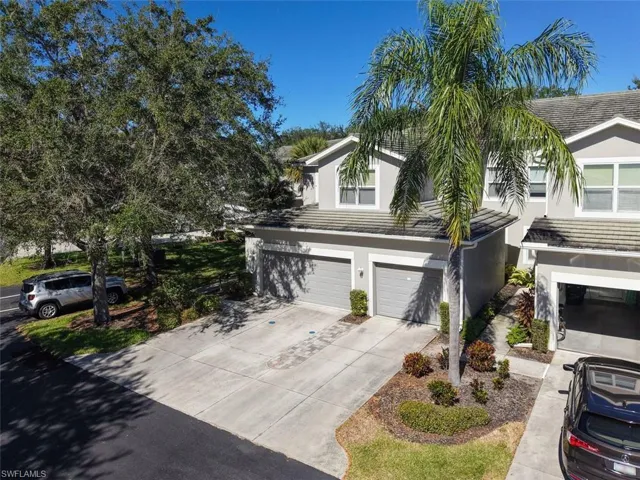Traditional-style home with stucco siding, concrete driveway, an attached garage, and a tile roof