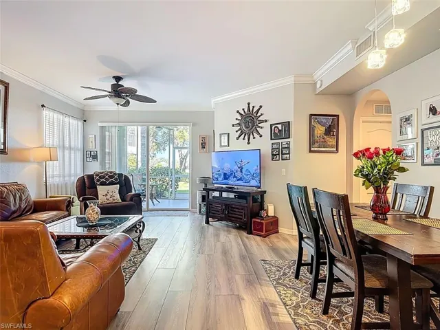 Living room featuring arched walkways, crown molding, wood finished floors, and ceiling fan