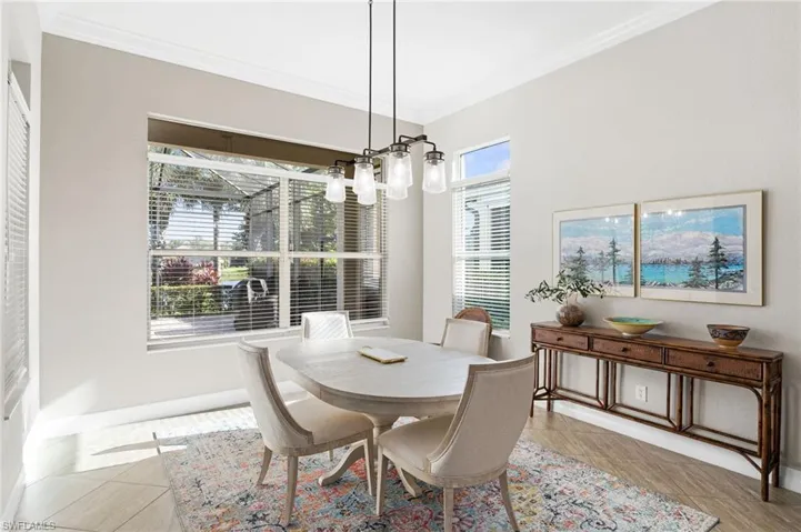 Dining area featuring crown molding, neutral wall finishes, tile flooring, and a multi-light metal pendant fixture