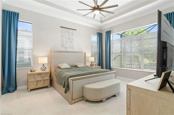 Tray ceiling with recessed lighting, multi-blade ceiling fan, and large windows with horizontal blinds