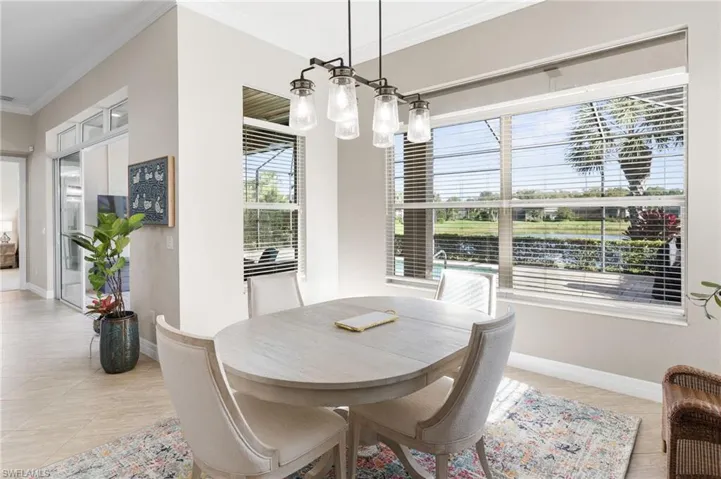 Multi-paneled windows with horizontal blinds, iron-finish multi-light chandelier, crown molding, and neutral tile flooring