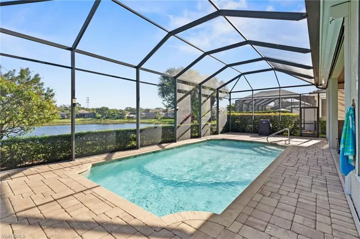Screen-enclosed pool featuring concrete paver decking, a built-in step entry, and water frontage