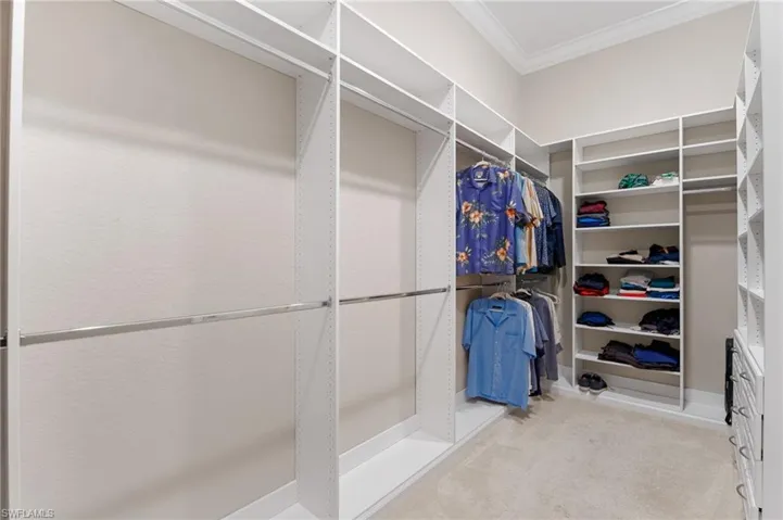 Walk-in closet featuring white built-in shelving, adjustable storage cubbies, integrated clothing rods, and drawer storage