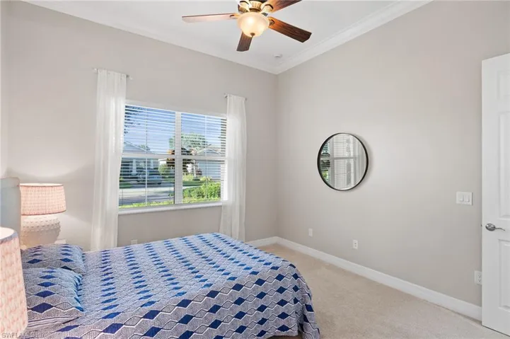 High ceilings with crown molding, ceiling fan with light fixture, large window with natural light, and neutral carpeting