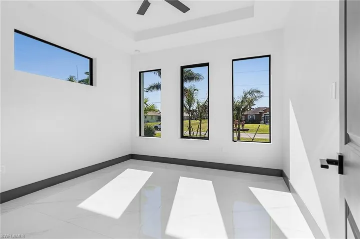 Empty room featuring ceiling fan, a healthy amount of sunlight, and a raised ceiling