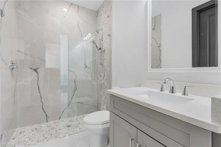 Bathroom with vanity, toilet, and a tile shower
