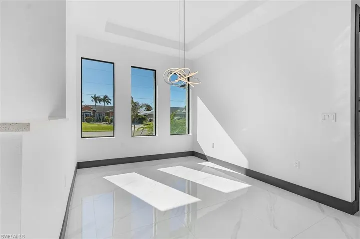 Spare room featuring a tray ceiling and a notable chandelier