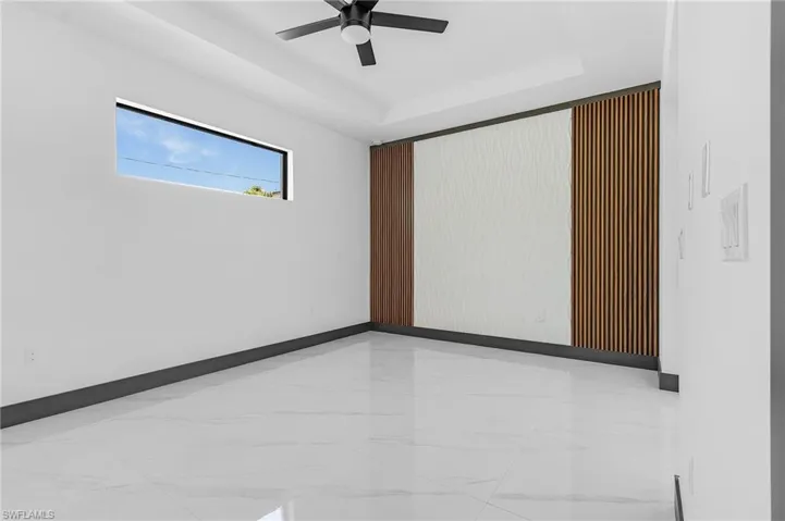 Spare room featuring a raised ceiling and ceiling fan