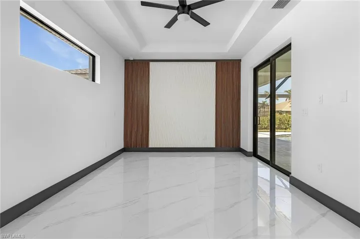 Unfurnished room featuring ceiling fan, a wealth of natural light, and a tray ceiling