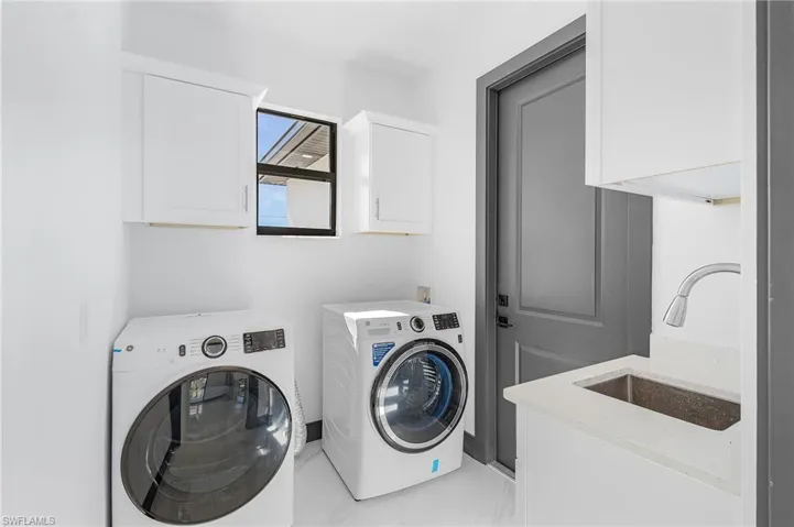 Laundry area featuring cabinets, independent washer and dryer, and sink