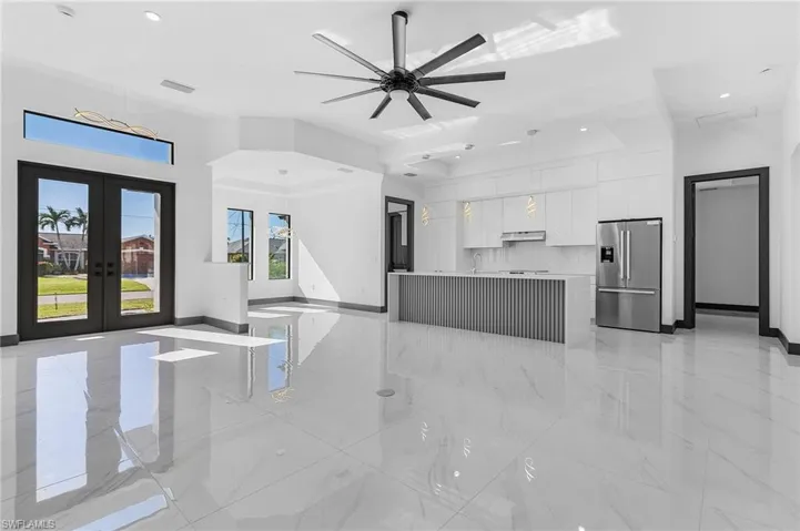 Unfurnished living room with ceiling fan, sink, and french doors