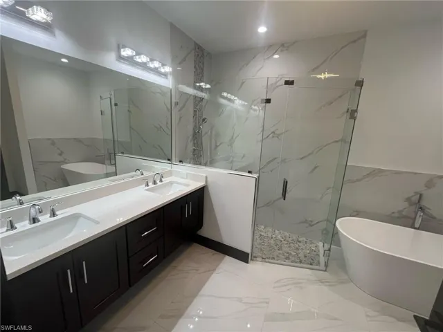 Bathroom featuring plus walk in shower, vanity, and tile walls