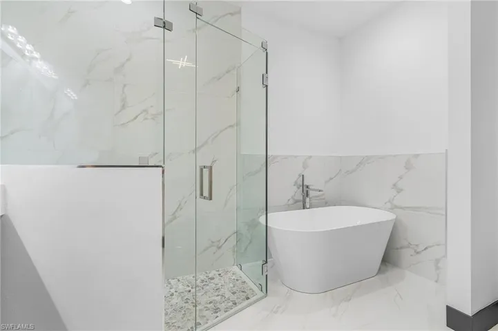 Bathroom featuring independent shower and bath and tile walls