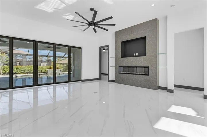 Spare room with a tiled fireplace and ceiling fan