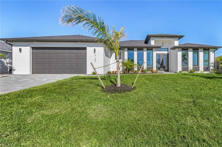 View of front of property with a garage and a front lawn