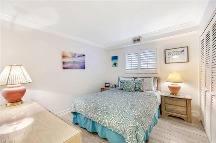 Bedroom with crown molding, wood finished floors, and a closet