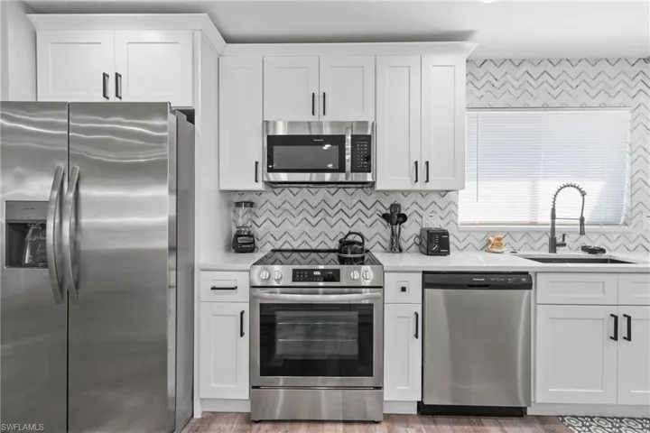 Kitchen featuring white cabinetry, light countertops, a sink, and stainless steel appliances