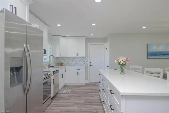 Kitchen featuring sink, stainless steel appliances, white cabinets, a kitchen island, and decorative backsplash