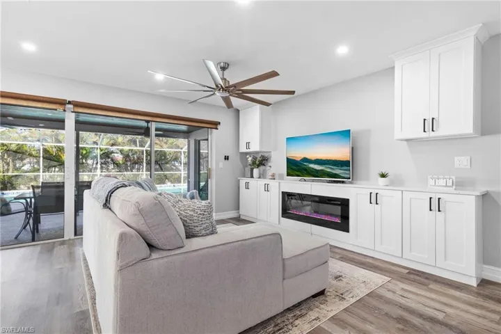 Living room with recessed lighting, baseboards, light wood-style floors, a ceiling fan, and a glass covered fireplace