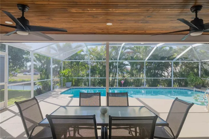 View of pool with a patio, ceiling fan, and glass enclosure