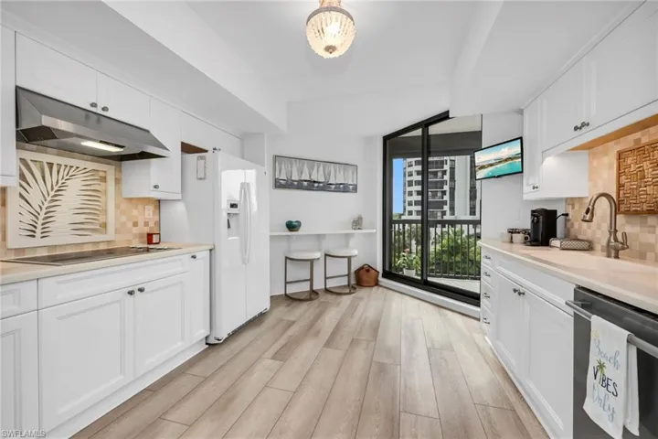 Kitchen Featuring White Cabinets, Under Cabinet Range Hood, and Sliding Door Access to Balcony
