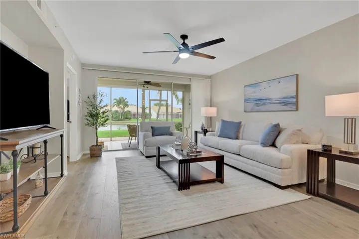 Living room featuring light wood-style floors, ceiling fan, and a water view