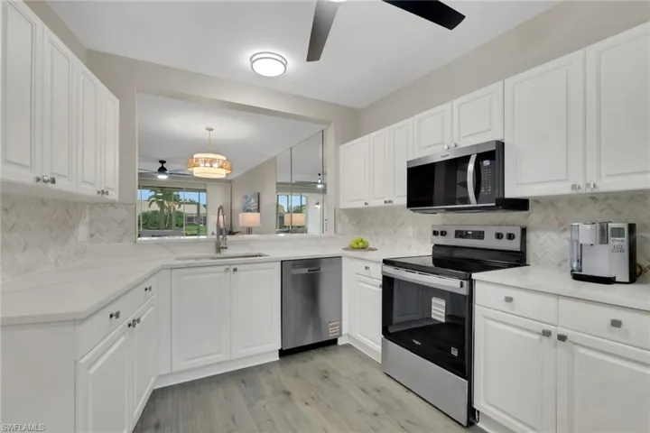 Kitchen with appliances with stainless steel finishes, ceiling fan, white cabinets, and backsplash