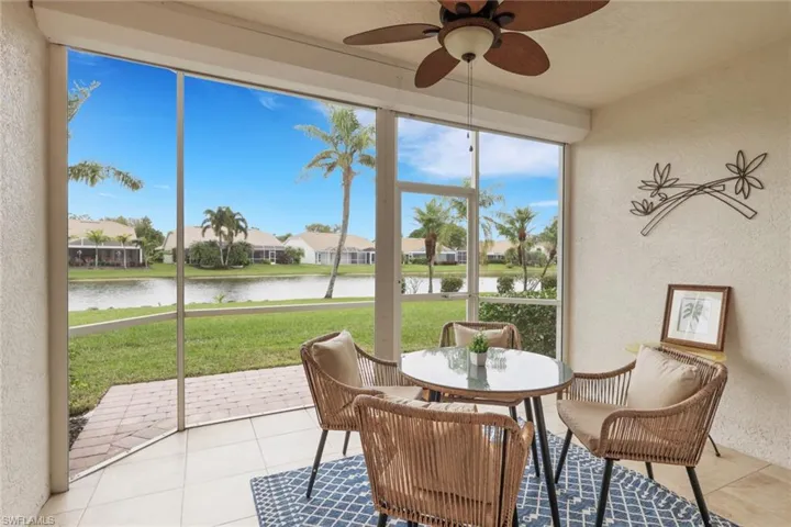 Sunroom featuring a textured wall, a water view, a residential view, and tile patterned flooring