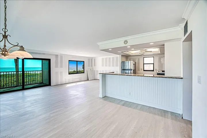 Kitchen with plenty of natural light, open floor plan, crown molding, and light wood-style flooring