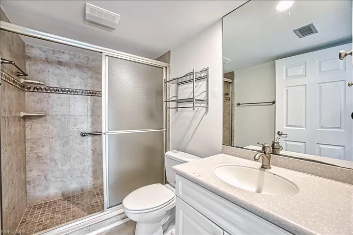 Full bathroom with vanity, visible vents, toilet, and a shower stall