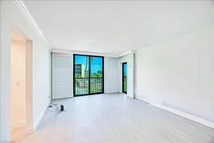 Unfurnished room with floor to ceiling windows, ornamental molding, baseboards, and light wood-type flooring
