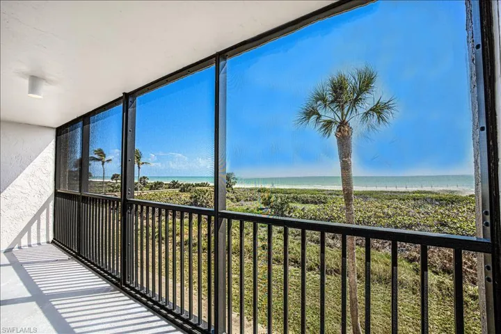 Unfurnished sunroom featuring a water view, a healthy amount of sunlight, and a beach view