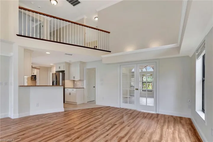 Unfurnished living room with towering ceiling, crown molding, light hardwood / wood-style floors